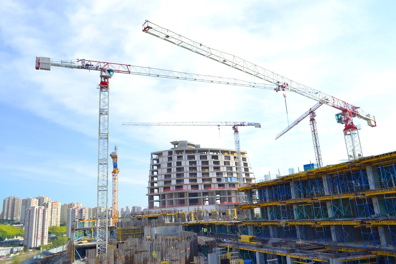 Urban construction site featuring multiple tower cranes against a city skyline.