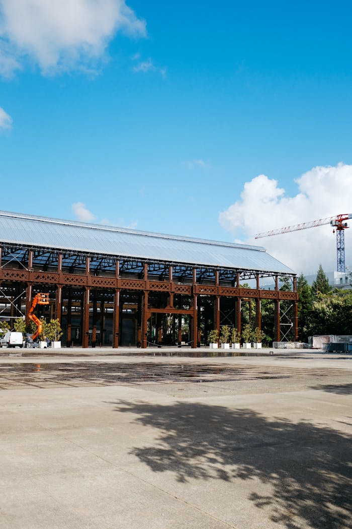 Exterior view of a modern industrial plant with a crane against a bright blue sky, suggesting construction.